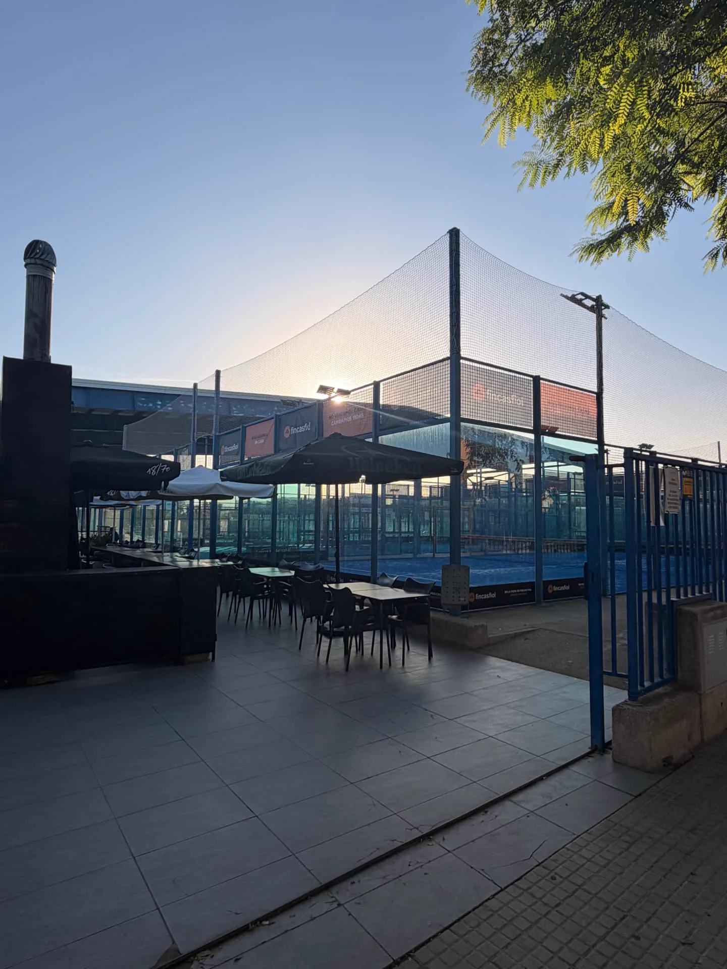 Outdoor padel court at sunset behind the net